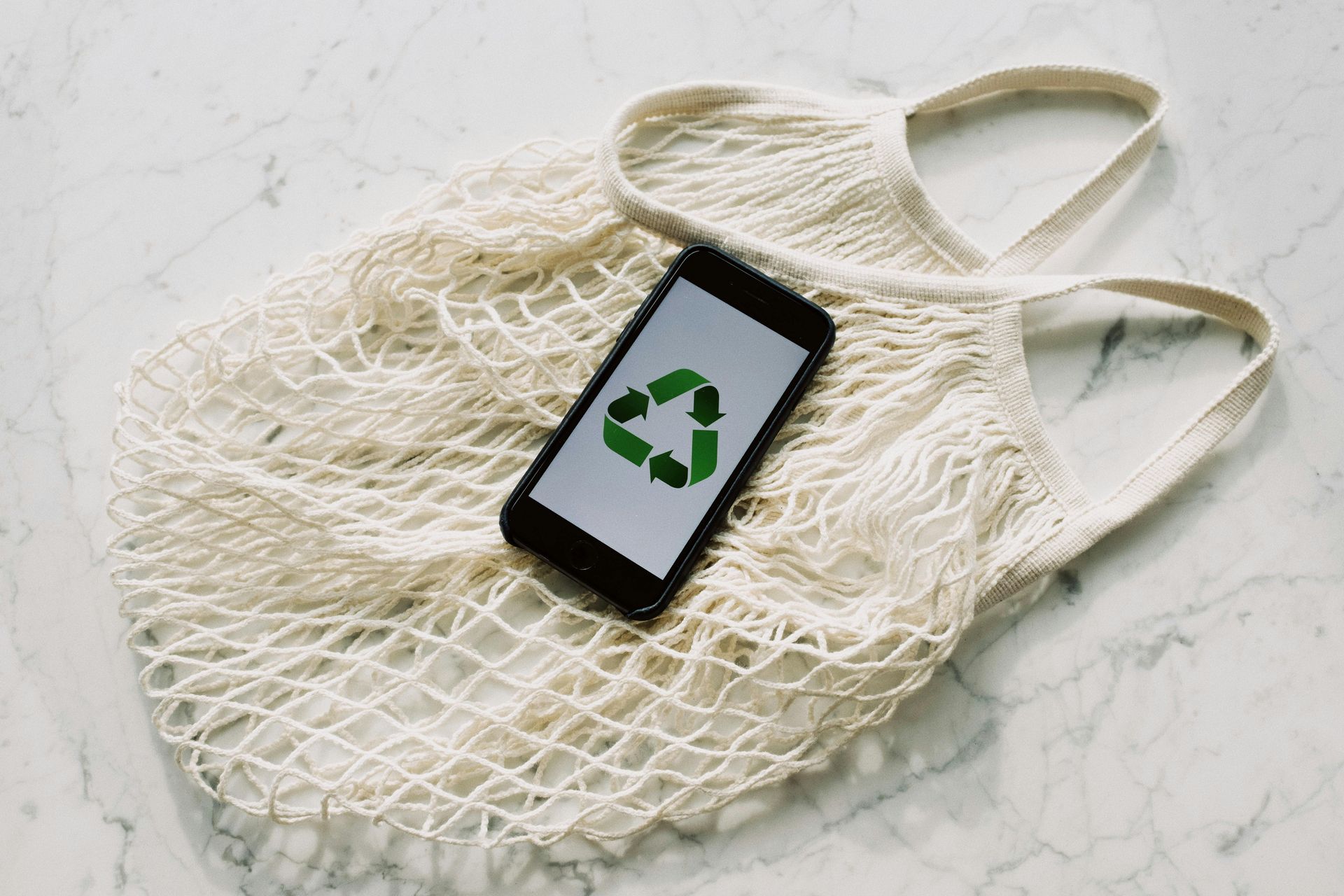 Smartphone showing a recycling symbol on a mesh bag